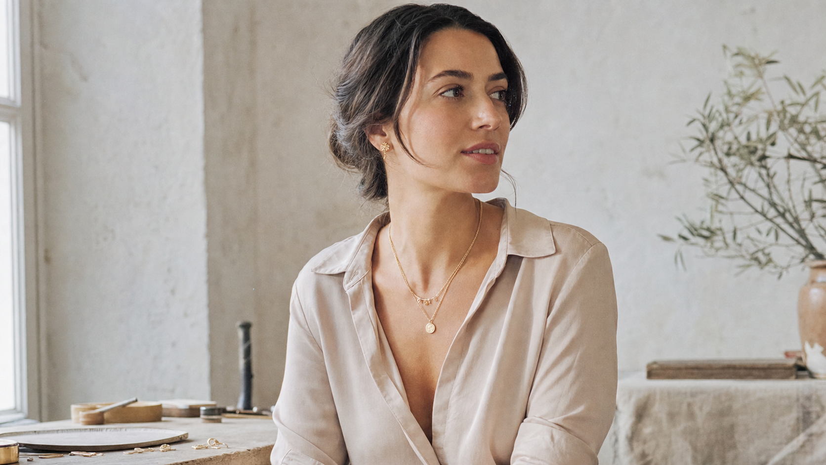 Woman wearing personalized Suri necklaces in a dark jewelry atelier