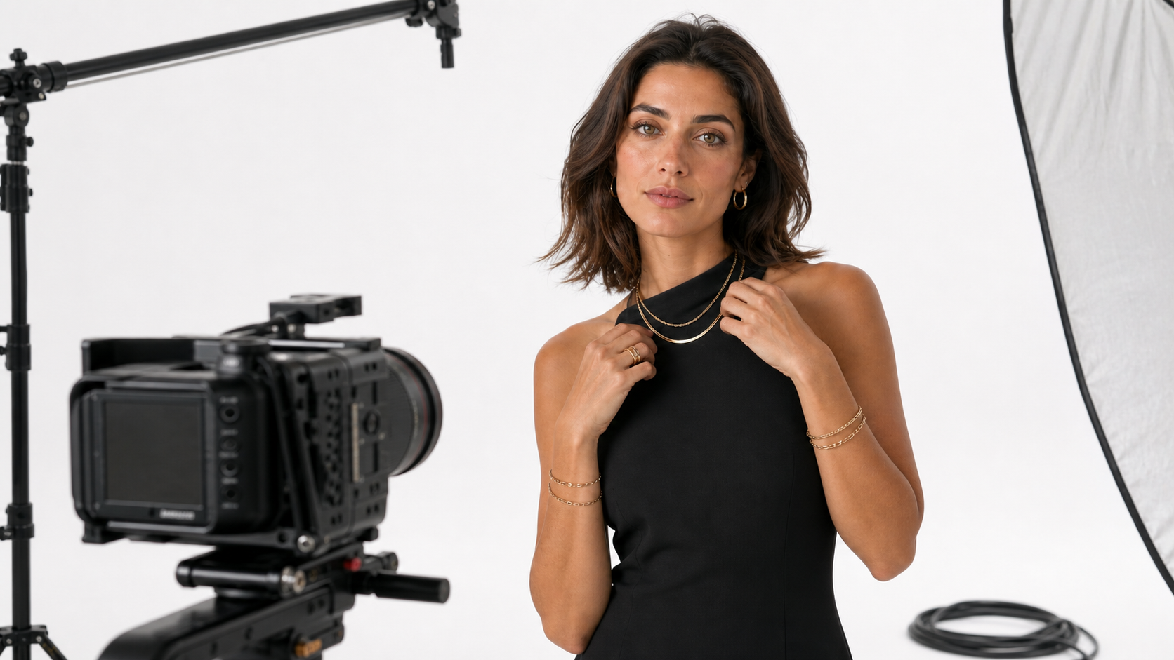 Suri model wearing layered jewelry on a white campaign film set